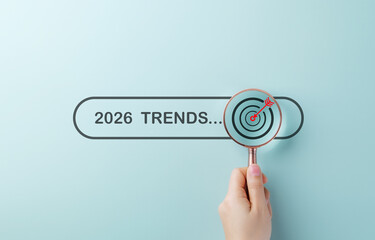 Searching Business Trends for 2026. A hand holding magnifying glass over search bar 2026 Trends,...