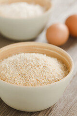Fine crispy breadcrumbs in bowl, with eggs and flour in the back, ingredients of the breading or...