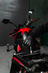 Technician carefully removes the motorcycle seat using tools to access internal components for...