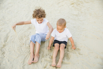 boy and girl blonde, brother and sister play in the sandbox and have fun