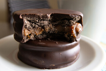 A bitten alfajor on top of a whole alfajor inside a small plate