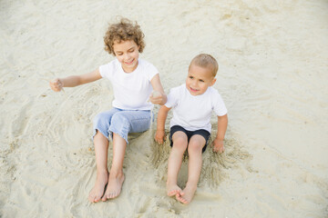 boy and girl blonde, brother and sister play in the sandbox and have fun