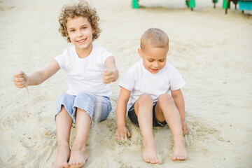 boy and girl blonde, brother and sister play in the sandbox and have fun
