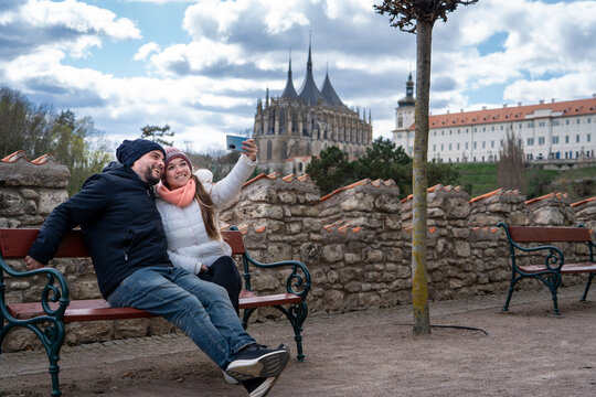 Pareja de turistas tom&aacute;ndose una selfie en una plaza de kutn&aacute; hora, con la Catedral de fondo