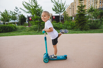 A boy of 4-5 years old rides a scooter in a city park.