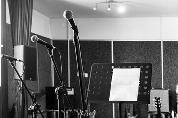 Musicians practice in a sound studio with microphones and sheet music present