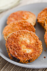 Fried breaded eggplant aubergine slices, vegetarian cutlet, milanese or schnitzel served on blue plate (Selective Focus, Focus one third into the image)