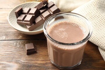 Chocolate milk in glass and ingredient on wooden table, closeup