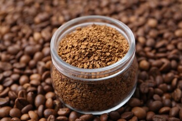 Glass jar with granulated instant coffee on beans, closeup