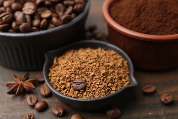 Different types of instant coffee and beans in bowls on wooden table, closeup