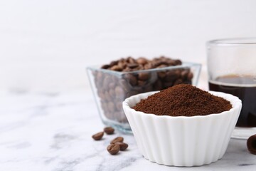 Instant coffee powder in bowl, beans and drink on white marble table, closeup. Space for text