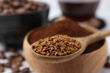 Granulated instant coffee in spoon and bowl on light table, selective focus