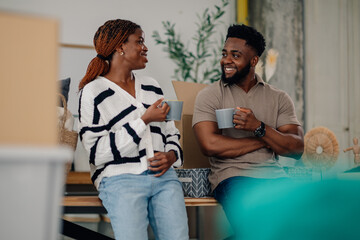Fototapeta premium Happy couple drinking coffee during break from moving into new home