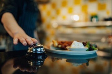 Chef ringing service bell for ready meal in restaurant kitchen
