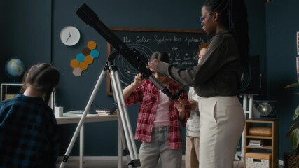 While Black female teacher and students engaged with telescope in space-themed classroom, mischievous girl with glasses dashing playfully around them, adding fun to educational environment - Powered by Adobe