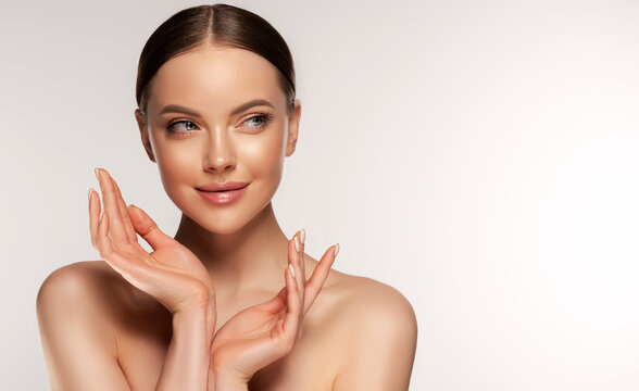 Fototapeta Beautiful young woman with clean fresh skin touching her face . Girl facial treatment . Cosmetology , beauty and spa . Female model, care concept