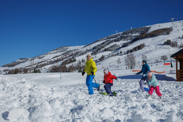 Joyful family sledding adventure on a bright, sunny snowy day