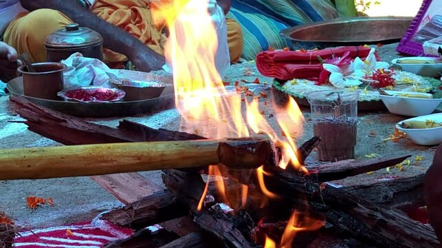 Hindu Brahman Priest Pouring Or Offering Ghee on Holy Fire While Chanting Mantras In Front Of Hindu God Or Goddess Statue, Slow Motion Horizontal Footage, Shot In India