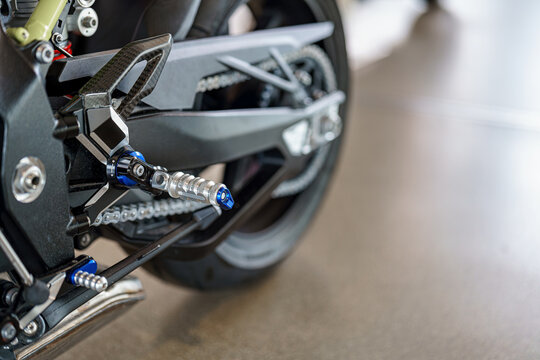 Close-up view of motorcycle footpeg and gear shift lever at a showroom highlighting modern design