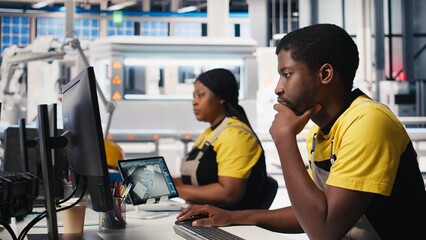 Black engineer works on solar software settings in automated factory, optimizing the production...