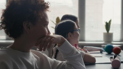 Curious diverse students attentively listening to Black female teacher during classroom astronomy lesson, with planet models and notebooks on their desks - Powered by Adobe