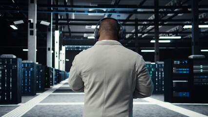 Admin walking in data center, listening music while doing inspection on infrastructure tech. IT...
