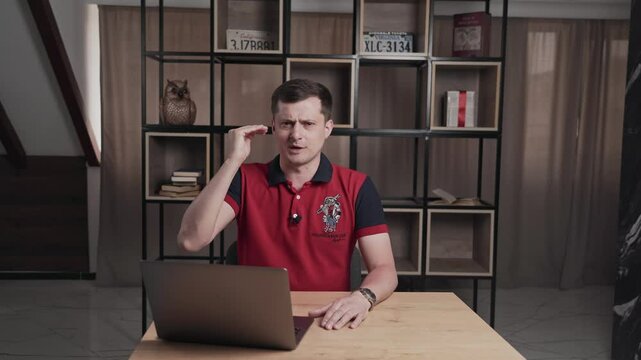 Interview or broadcast of program on television. Serious male at table with laptop is speaking looking at camera. Man presenter of sport educational and cognitive channel gestures with hands and talk.
