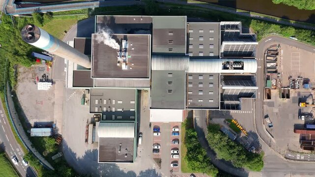 Aerial drone shot of large incineration plant near Stoke on Trent England UK. Waste incineration to energy with green trees, cityscapes and canal landscape industrial waste removal energy generation 