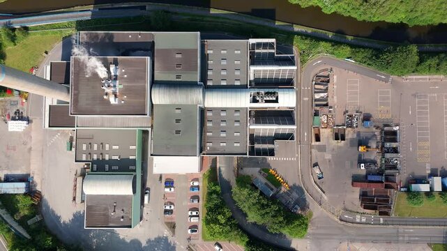 Aerial drone shot of large incineration plant near Stoke on Trent England UK. Waste incineration to energy with green trees, cityscapes and canal landscape industrial waste removal energy generation 