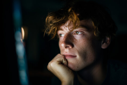 Atmospheric moody portrait of a young student deep in thought with dramatic lighting and intense expression