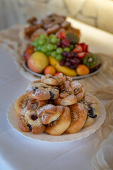 Various types of wedding pastries on a white plate with fruit in the background. 
