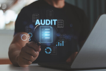 Audit business concept. Businessman using laptop and holding magnifying glass to check and evaluate financial statement, checklist auditing accounts within the organization.