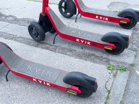 Ljubljana, Slovenia - June 03, 2025: Red electric scooters parked on urban pavement, showcasing the Kvik brand, ideal for city commuting and eco-friendly transportation solutions