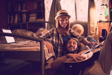 Young couple playing the guitar and singing in the bedroom together