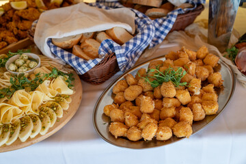 A metal bowl with fried cheese-filled balls on a buffet-style table. 

