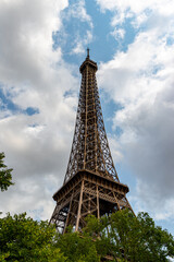 Eiffel Tower from Below with Trees and Cloudy Sky