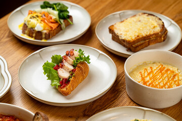 A charming brunch setting features an array of dishes, including savory croissants, creamy soups, and deliciously toasted bread. Lively colors inspire appetites and conversation