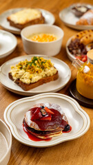 A lovely brunch table features fluffy pancakes with berry sauce, savory scrambled eggs on toast, and vibrant fresh fruits, creating a charming atmosphere for leisurely dining