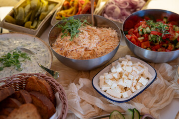 Cheese cubes and metal bowls with salad on the buffet table for guests.