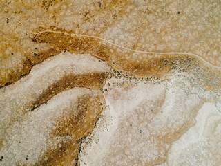 Aerial view of a dry, arid landscape in  Carrizo Plain National Monument, California, USA. The image shows a network of dirt roads and trails winding through the sparse vegetation.