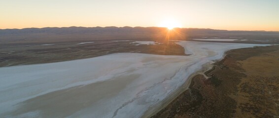Aerial view of Soda Lake in Carrizo Plain National Monument, California, USA. The sun rises over the mountains, reflecting on the salt lake. The image captures the beauty of the Australian outback.