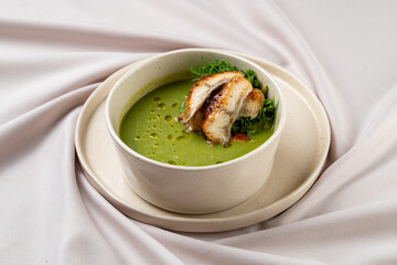 A vibrant green soup delights the senses with a perfect topping of grilled chicken, showcasing a harmony of flavors. Fresh herbs add a touch of elegance to this gourmet dish