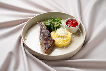 A beautifully arranged dish showcases a grilled fillet alongside creamy mashed potatoes topped with fresh herbs