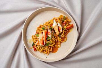 Tantalize your taste buds with this beautifully presented plate of seafood noodles, featuring fresh ingredients and vibrant colors, set against a soft, neutral fabric that adds elegance
