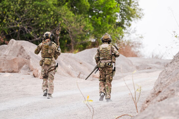 Modern Soldiers on Recon Mission – Two Armed Men in Military Camouflage Patrolling a Rocky...