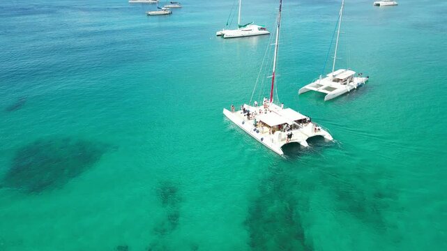 Bright daytime drone footage of excursion boats and catamarans floating in the calm turquoise waters of Bayahibe Bay, Dominican Republic.Ideal for travel videos, tourism ads, or Caribbean destination 