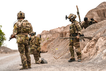 Special Forces Team Standing Together in Desert Mountain Terrain – Tactical Soldiers in Full Gear...