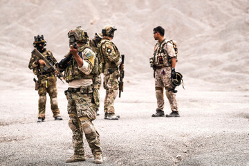 Special Forces Team Standing Together in Desert Mountain Terrain – Tactical Soldiers in Full Gear...