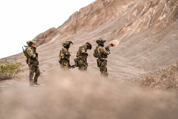 Special Forces Team Standing Together in Desert Mountain Terrain – Tactical Soldiers in Full Gear...