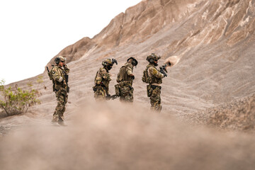 Special Forces Team Standing Together in Desert Mountain Terrain – Tactical Soldiers in Full Gear...